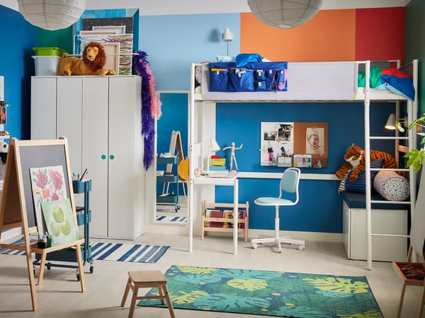 ブルーの壁に白い家具を合わせた子ども部屋。学習机と収納棚で整理しやすいレイアウト。