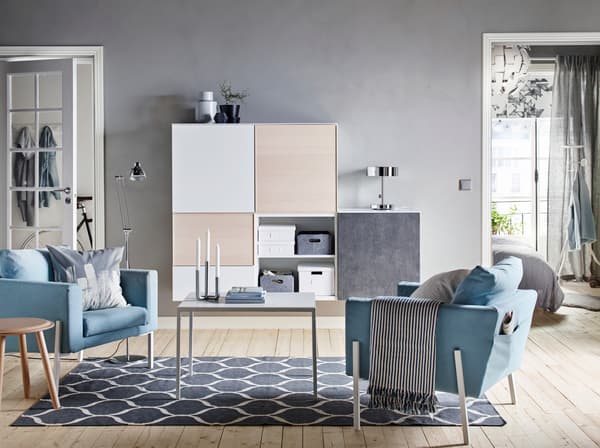 ブルーのソファと幾何学柄ラグを合わせた北欧風リビング。木製家具と収納でシンプルな空間。