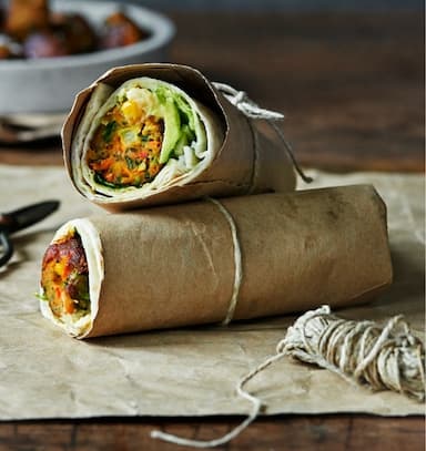 Burrito de mandonguilla vegetal amb alvocat servit en paper de forn i subjectat amb un cordill.