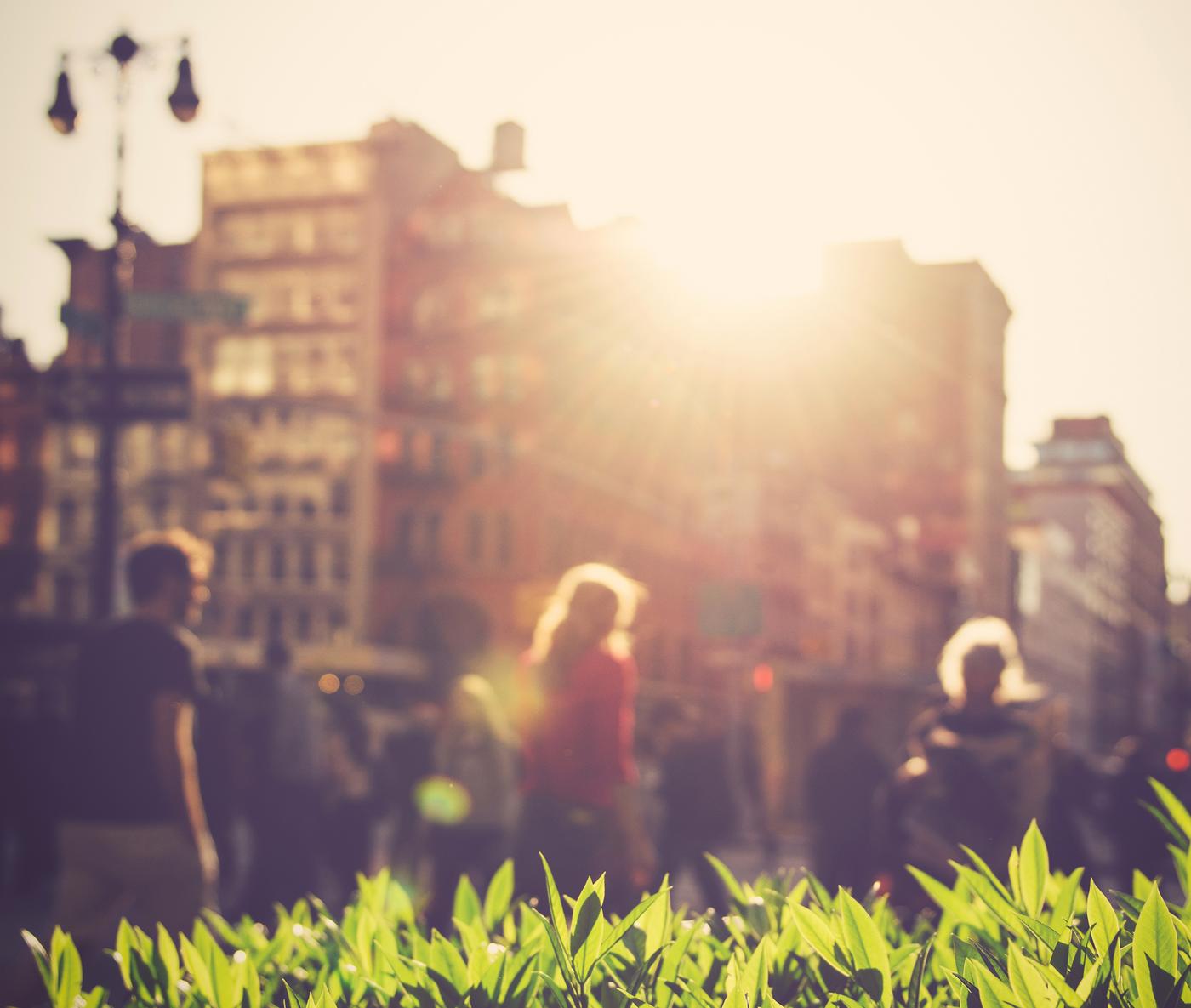 Bylandskap med mennesker og biler i bevegelse. 