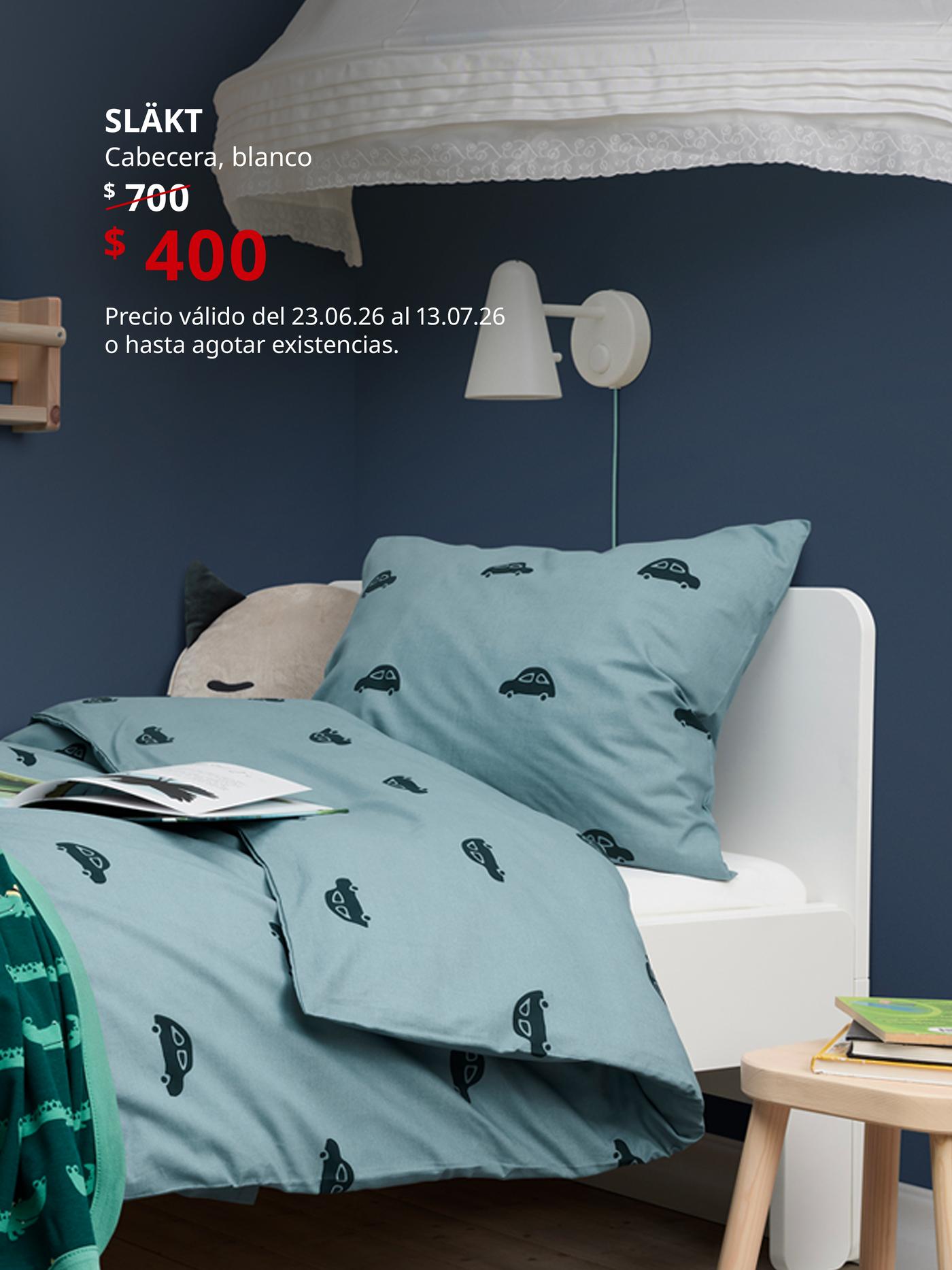 Cabecera SLÄKT blanca en habitación infantil con ropa de cama estampada, lámpara de pared y mesita auxiliar