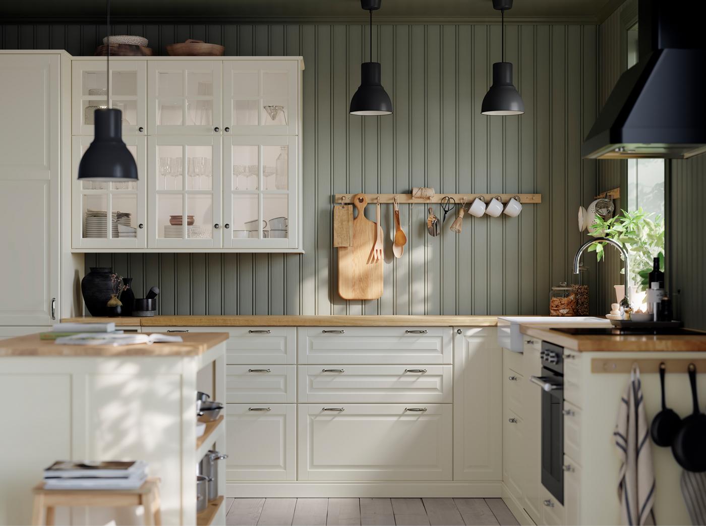 Cabinets with BODBYN glass doors in off-white, storage with BODBYN doors in off-white and kitchen items hang from hooks.