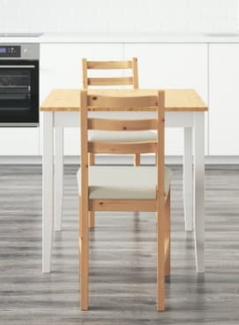 Cadira de cuina de fusta al costat d'una taula blanca i fusta d'IKEA.