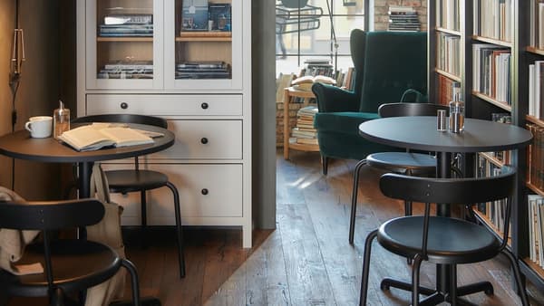 Café mit Cafémöbeln und großen Bücherausstellungen in Bücherschränken, Scheinwerfern und einem Sessel mit hoher Rückenlehne aus grünem Samt.