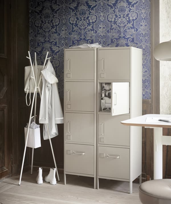 Caisson à tiroirs métallique beige avec fournitures rangées dans un organiseur posé dessus, à côté d'un bureau.