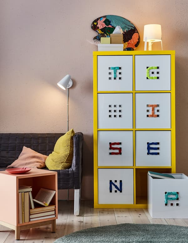 Caixes IKEA LEKMAN en blanc en un armari groc.