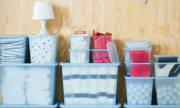 Cajas de diferentes tamaños, translúcidas y organizadoras llenas de objetos y lámpara pequeña blanca.