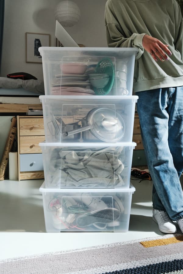 Cajas de plástico organizadoras SAMLA junto a una persona con jeans y poleron verde.