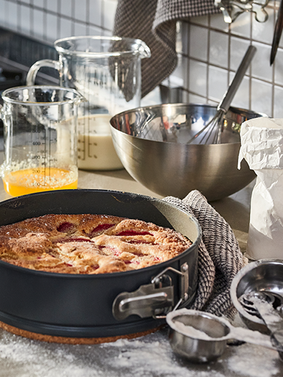 Cake in spring form pan, mixing bowl and measuring cups
