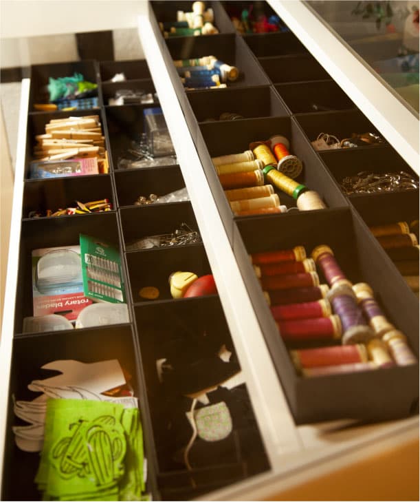 Calaixos amb compartiments plens de material de costura com fils, agulles, botons i tisores.