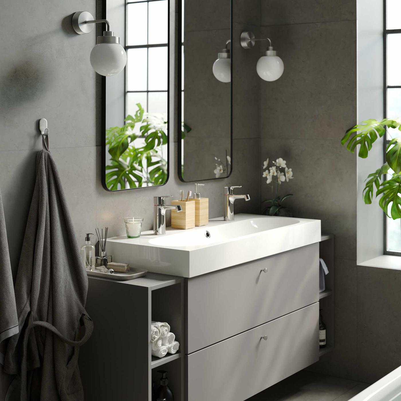 Calm relaxing bathroom with modern elegant bathtub, wide double sink with storage , double mirrors and indoor green plants.