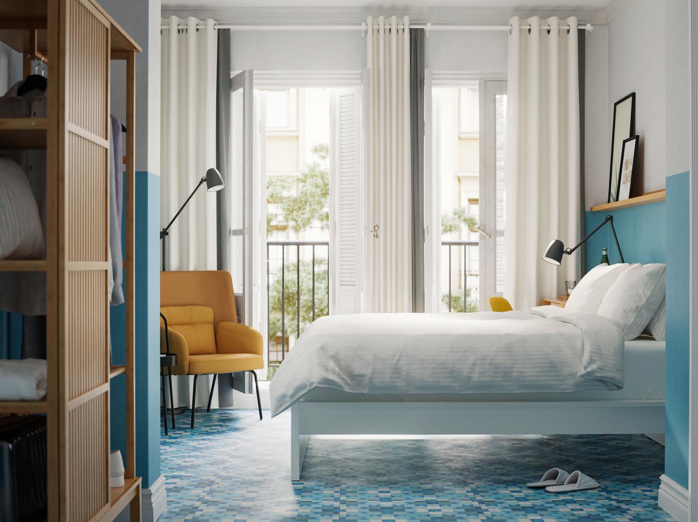 Cama blanca con cubrecama blanco apoyada en paredes celestes.