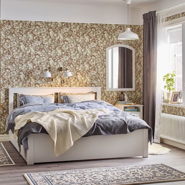 Camera da letto tradizionale beige, azzurra e bianca con carta da parati floreale e letto, comodino e cassettiera SONGESAND bianchi – IKEA