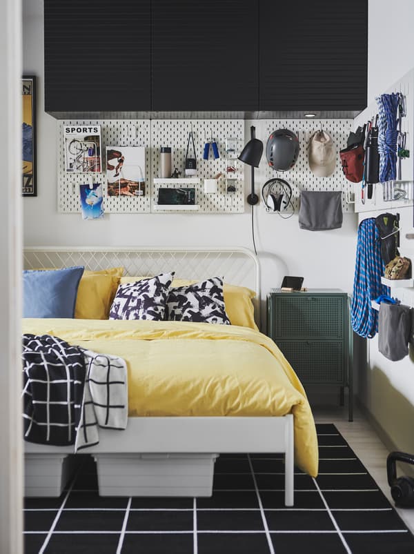 Cameretta con letto NESTTUN e pannelli portaoggetti SKÅDIS sulle pareti, dove sono appesi vari accessori e attrezzature per l’arrampicata.