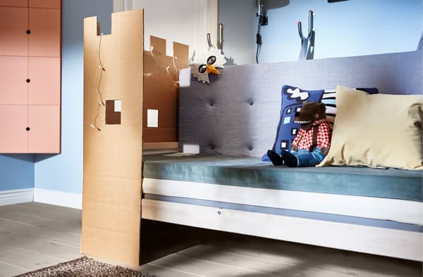 Canapé constitué de matelas, avec des coussins et une paroi ludique en carton