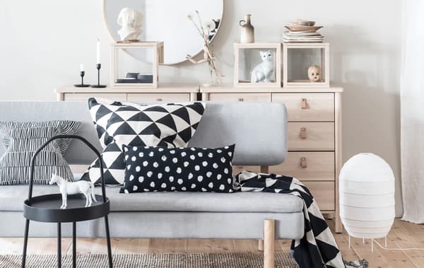 Canapé-lit YPPERLIG, articles textiles noir et blanc dans un salon comptant des meubles en bois clair et une déco minimaliste.