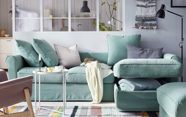 Canapé polyester IKEA GRÖNLID en vert avec compartiment de rangement ouvert sur une couverture bleue.