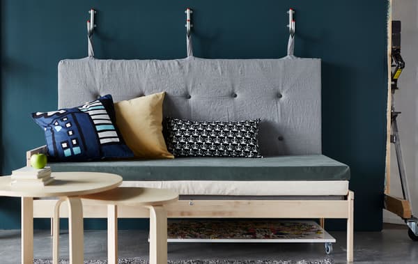 Canapé réalisé avec des matelas, avec dossier fixé à des crochets muraux.