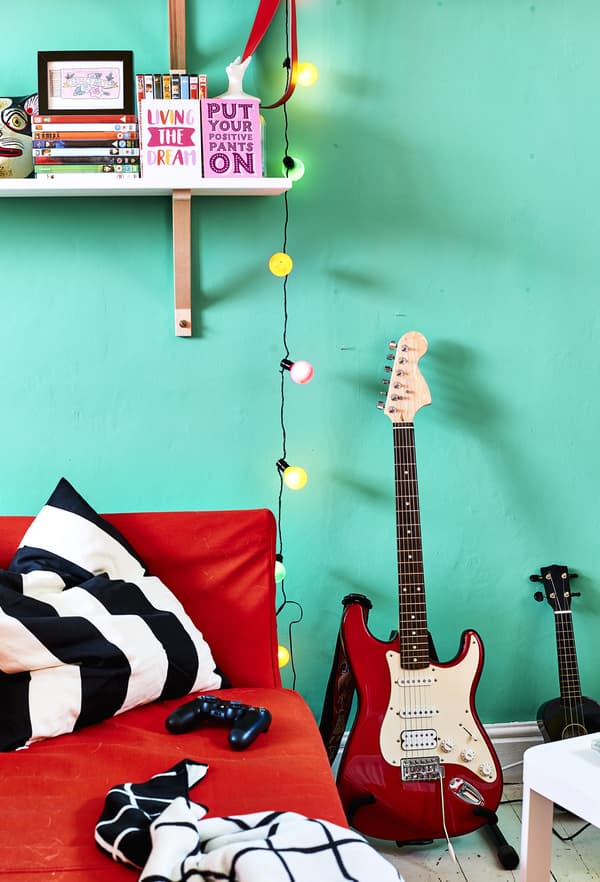 Canapé rouge et guitare posée contre un mur vert.