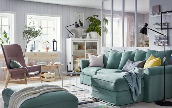 Canapé vert avec rangement IKEA GRÖNLID, rangement HEMNES en bois teinté blanc avec portes vitrées et banc INDUSTRIELL en pin naturel non traité dans un séjour apaisant.