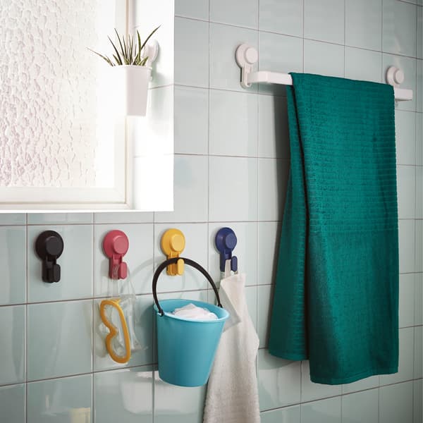 Cangkuk dengan cawan sedut TISKEN IKEA dalam pelbagai warna diletakkan pada dinding bilik mandi berwarna hijau lembut. Mainan dan tuala digantungkan di sana.