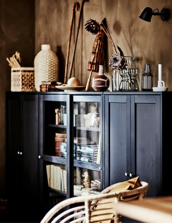 Canto de uma sala com um armário HAVSTA amplo e grande, repleto e coberto de objetos decorativos em materiais naturais.