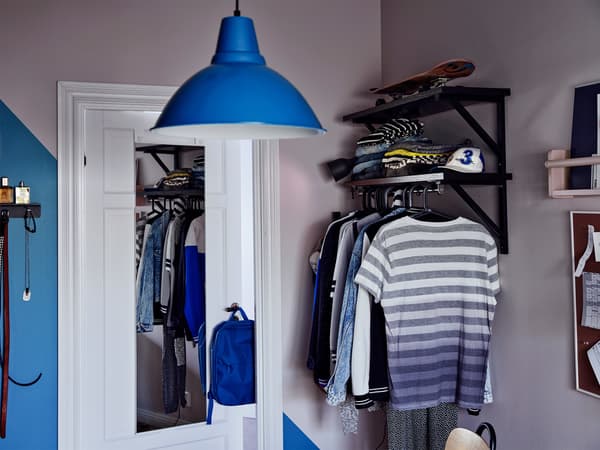 Cantó d'una habitació amb un mirall a la porta, un llum de sostre blau i roba penjada.
