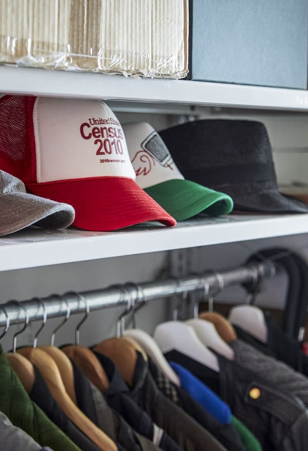 Caps on a shelf above a coat rail.