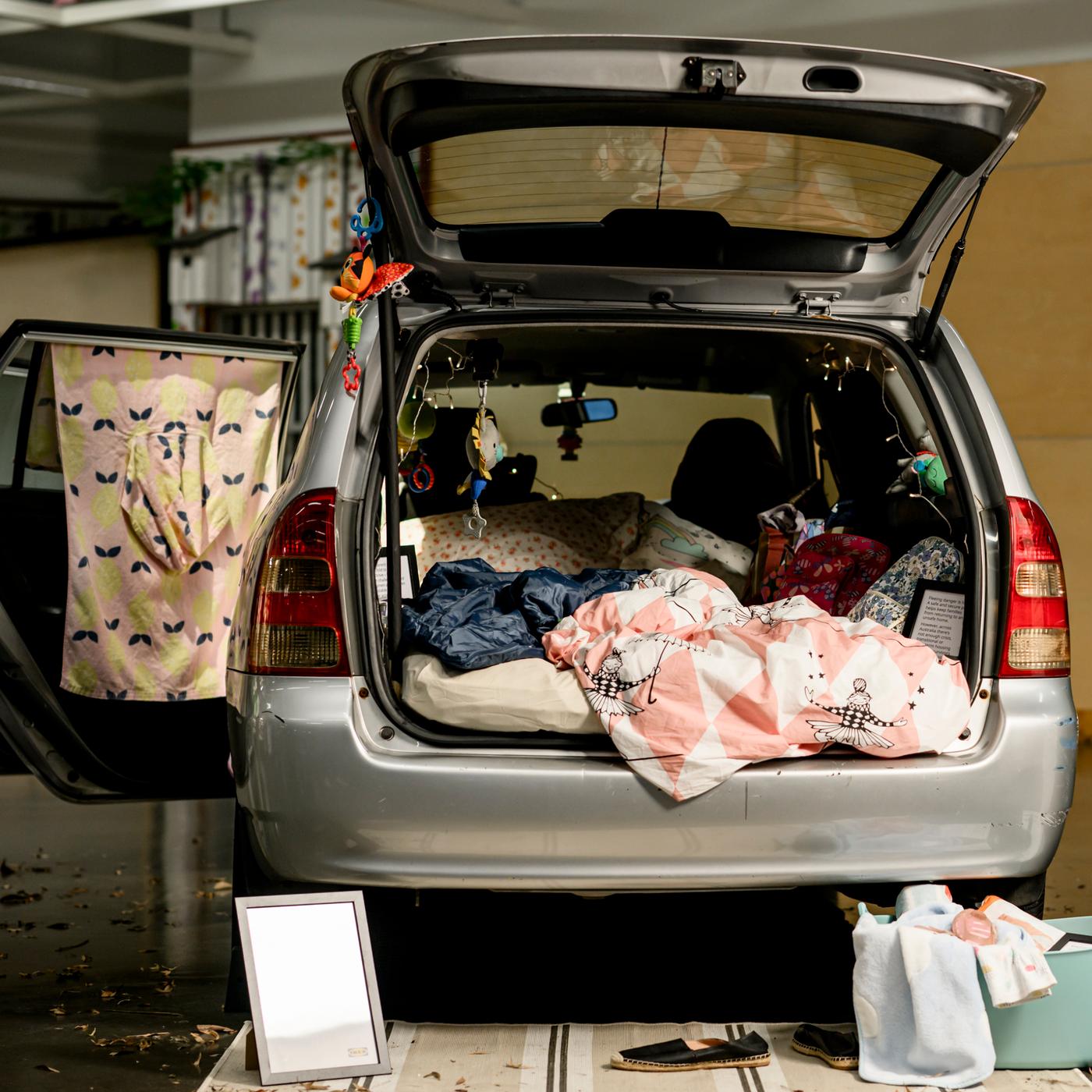 car boot opened showing living sitation for a family living in their car due to homelessness