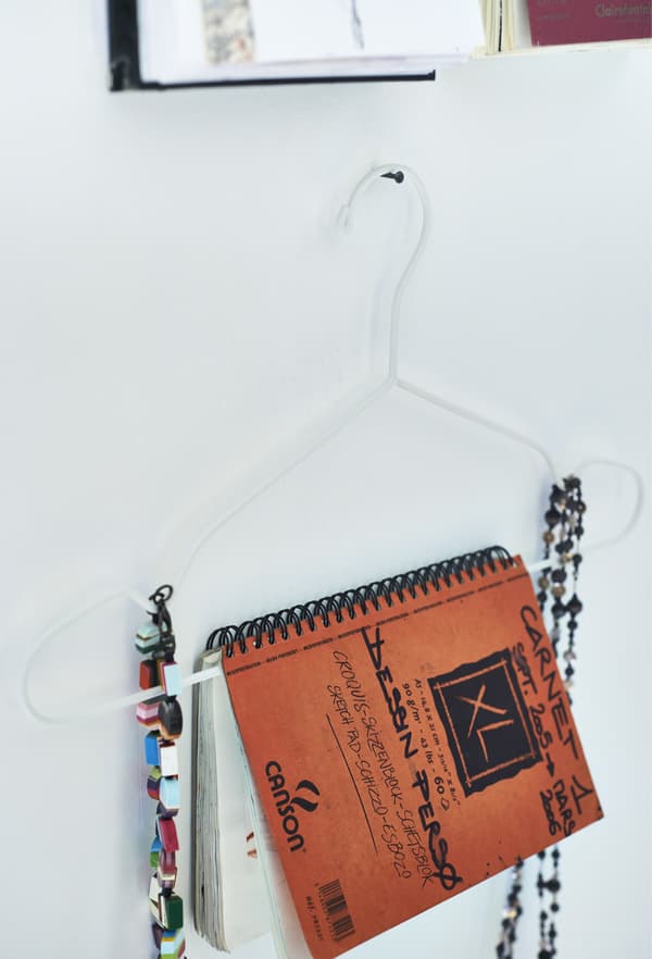 Carnet et bijoux présentés sur un cintre.