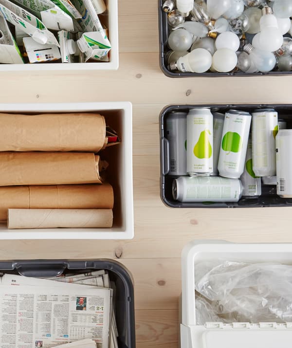Cartóns, xornais, lámpadas, latas e plástico clasificados en caixas de reciclaxe.