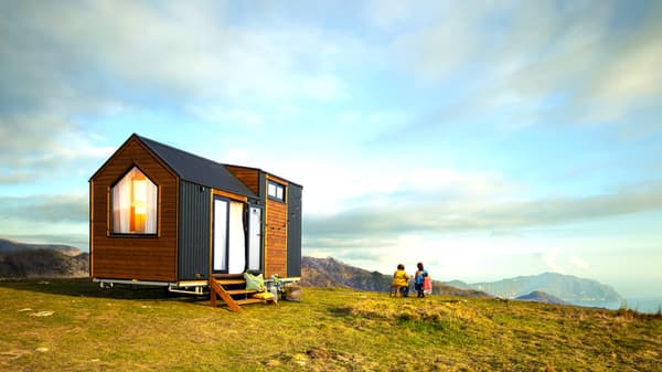 Casetta mobile in legno su un prato in un paesaggio montano.