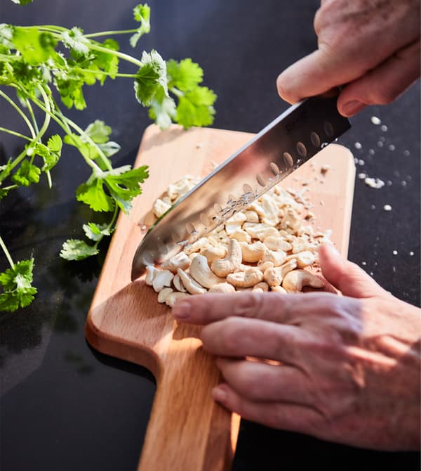Cashews are being chopped on a chopping board.