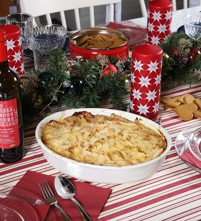 Casserole with potatoes and sprats arond chritmas themed drinks, napkins, candles