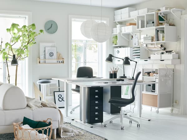 Ce bureau à la maison tout blanc reste organisé grâce à un mur de rangement créé avec des armoires et des étagères murales IKEA EKBY. Laissez entrer la lumière et mettez-vous au boulot!