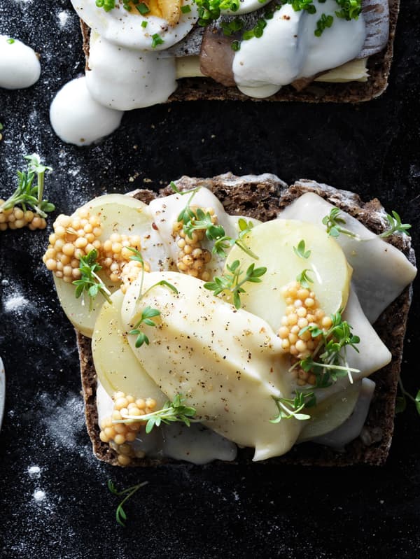 Celozrnný chlieb obložený marinovaným sleďom s kôprom SILL DILL, plátkami uvarených zemiakov, naloženými horčicovými semienkami a žeruchou.