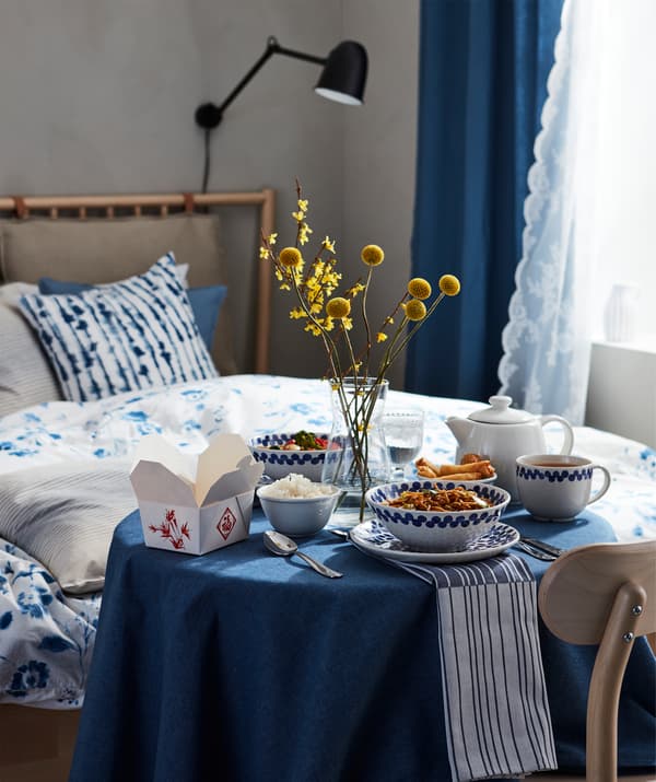 Cena in stile orientale con varie ciotole su un piccolo tavolo rotondo accanto a un letto.