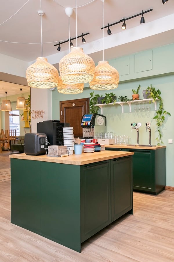 Central café counter with coffee machines, colorful mugs, and hanging rattan lamps.