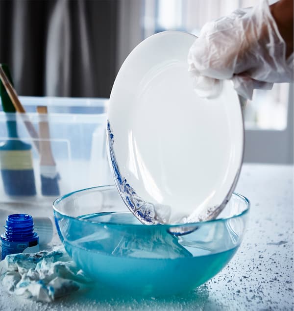 Čerstvo namaľovaný okraj taniera IKEA FÄRGRIK namočený do misky s vodou.