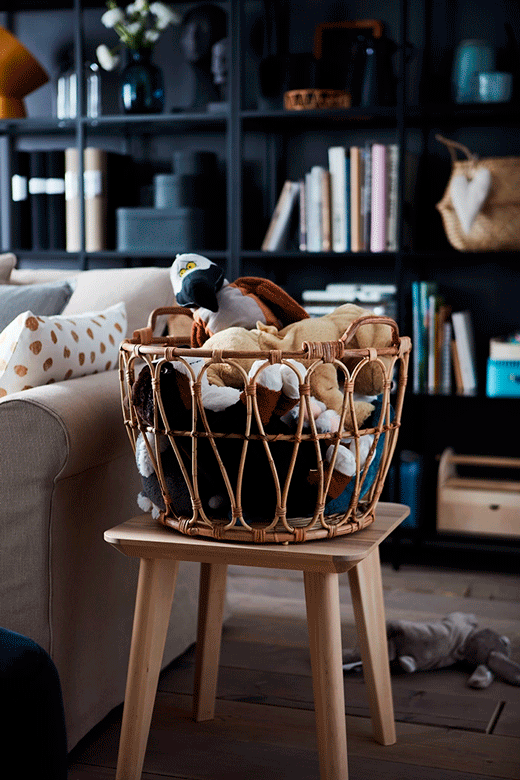 Cestino in rattan su uno sgabello in soggiorno pieno di animali di peluche - IKEA