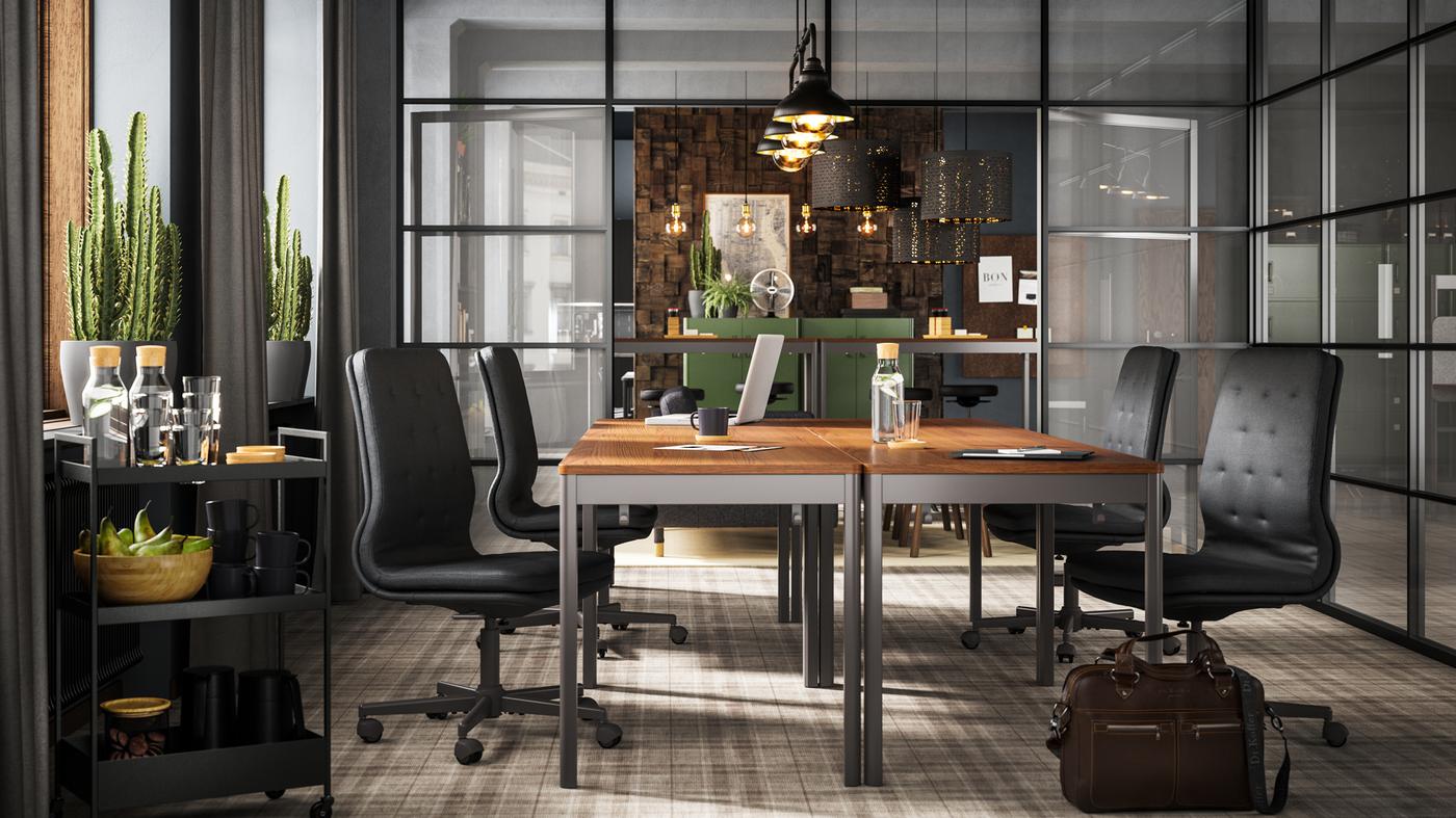 Četiri smeđa/tamnosiva IDÅSEN stola s tamnosivim stolicama prikazani u konferencijskoj sobi sa staklenim stijenama.