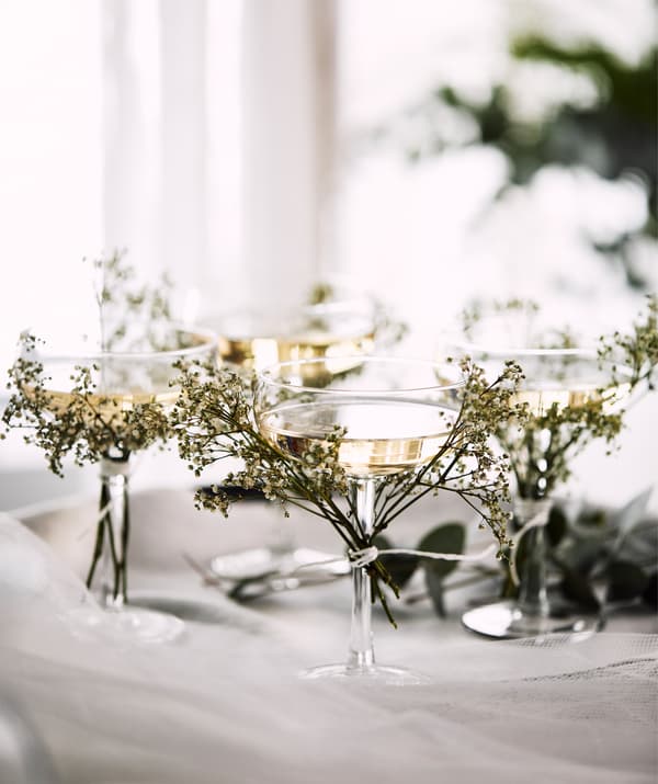 Četiri STORHET čaše za šampanjac na poslužavniku s malim graničicama malog divljeg cvijeća privezanim za stalak čaše.