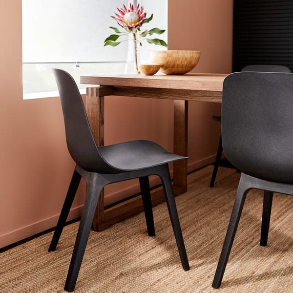 Chairs in anthracite, a jute rug and a table in brown stained oak veneer with bowls in bamboo on the table top.