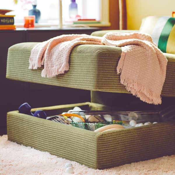 Chaise longue JÄTTEBO berwarna kuning-hijau gelap yang mempunyai petak storan tersembunyi dibuka, menunjukkan barang-barang di dalamnya.