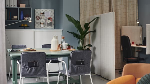 Chaises conférence LÄKTARE disposées autour d’une table pliante MITTZON avec roulettes, dans un bureau aux murs bleus.