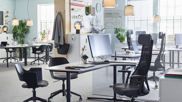 Chaises de bureau noires réglables JÄRVFJÄLLET et bureaux assis/debout dans un bureau ouvert