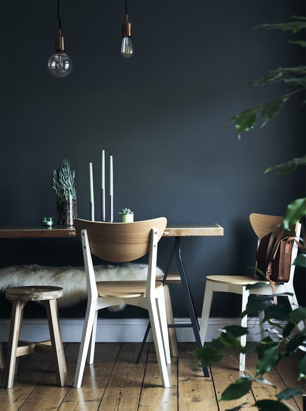Chaises et table sur fond de mur bleu foncé.