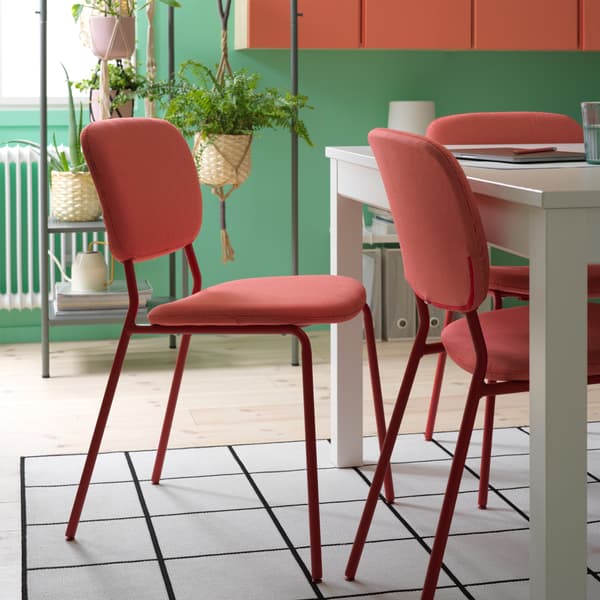 Chaises rouges, table blanche et tapis à carreaux noirs et blancs.