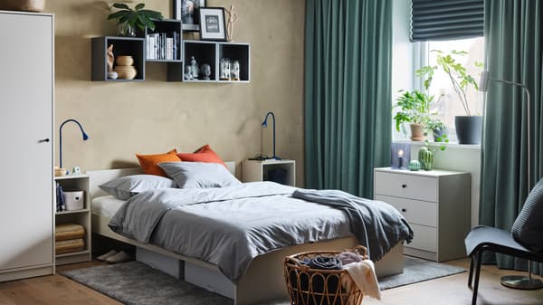 Chambre à coucher avec cadre et tête de lit, garde-robe, table de chevet et commode, le tout en beige clair.
