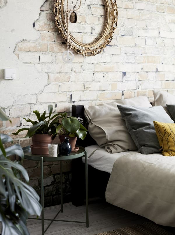 Chambre à coucher avec mur en briques apparentes et plantes.